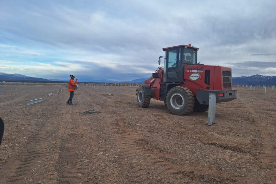 trabajador en obra en desierto junto a retroexcavadora