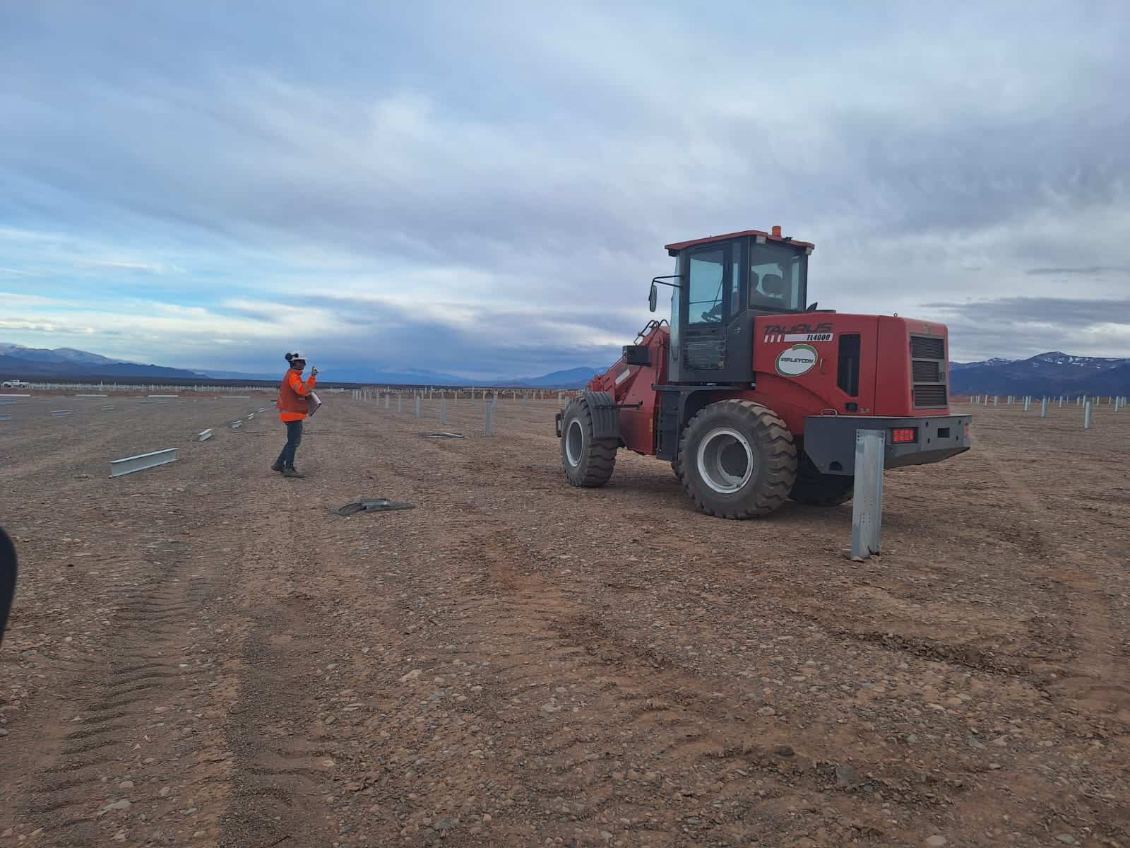 trabajador en obra en desierto junto a retroexcavadora